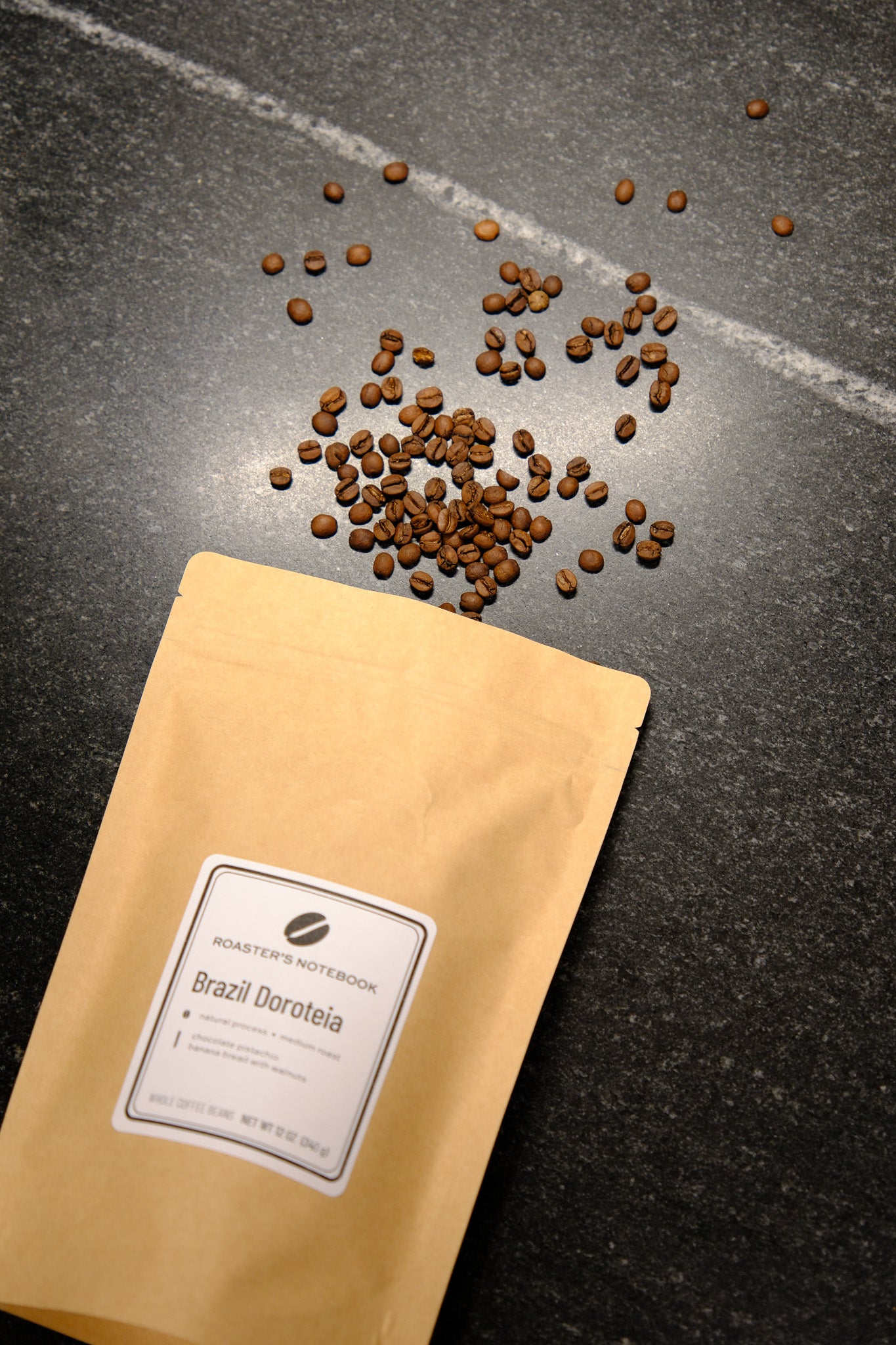 Coffee beans spilling out of a yellow coffee bag on a dark surface