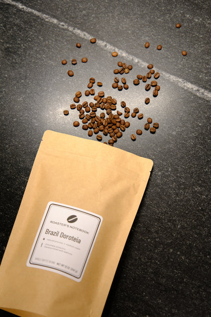Coffee beans spilling out of a yellow coffee bag on a dark surface